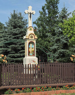 Przydrożny krzyż z kapliczką stojący w centrum wsi. Różanna, gmina Odrzywół, powiat przysuski.