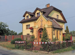 Kapliczka przydrożna przy drodze Ludwinów - Sołtyków, za nią budynek mieszkalny Trablice 91a. Trablice, gmina Kowala, powiat radomski.