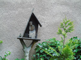 Kapliczka z Chrystusem Frasobliwym przed budynkiem przy ulicy Rębkowskiej 12. Warszawa, Praga Południe.