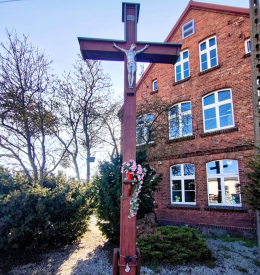 Krzyż drewniany obok szkoły im. Marii Konopnickiej. Dopiewiec, gmina Dopiewo. Powiat poznański, woj. wielkopolskie.