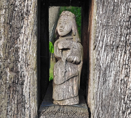 Figura święta, fragment kapliczki słupowej stojącej obok kaplicy Trójcy Świętej i św. Izydora. Grzebienisko, gmina Dusznik, powiat szamotulski, woj. wielkopolskie.